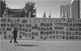  ?? HANNAH MCKAY/REUTERS ?? A child walks past posters with pictures of hostages kidnapped in the deadly Oct. 7 attack on Israel by the Palestinia­n Islamist group Hamas on Thursday in Tel Aviv, Israel.