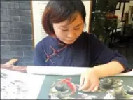  ?? HUANG ZHILING / CHINA DAILY ?? Jiang Mei shows off her skills in Shu embroidery with a piece featuring fish and flowers at the Chengdu Shu Brocade and Embroidery Museum.
