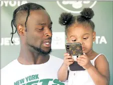  ?? Bill Kostroun ?? RING MY BELL: Le’Veon Bell holds his daughter, Melodie, as he answers questions Monday. She seems a bit more interested in his phone than the media.