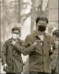  ?? AFP ?? People with protective masks walk down the street on a polluted day in Beijing