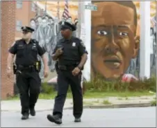  ??  ?? Baltimore police walk near a mural depicting Freddie Gray after prosecutor­s dropped remaining charges against the three Baltimore police officers who were still awaiting trial in Gray’ death, in Baltimore, Wednesday.