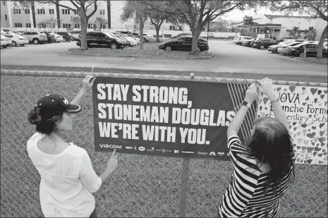  ?? SUSAN STOCKER/SOUTH FLORIDA SUN-SENTINEL VIA AP ?? Volunteers hang banners around the perimeter of Marjory Stoneman High School in Parkland, Fla., to welcome back students who will be returning to school today, two weeks after the mass shooting that killed 17 students and staff.