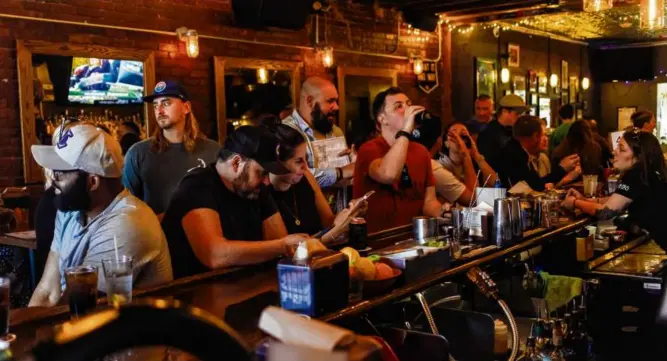  ?? PHOTOS BY CARLIN STIEHL FOR THE BOSTON GLOBE ?? Patrons enjoy food and drink at the Quiet Few. The East Boston tavern has a large whiskey selection (below left) and dishes such as the simple smash burger (below right).