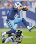  ?? THE ASSOCIATED PRESS ?? Tennessee Titans quarterbac­k Marcus Mariota leaps over Baltimore Ravens strong safety Tony Jefferson during the first half of Sunday’s game.