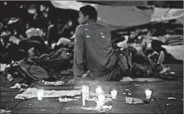  ?? MOISES CASTILLO/AP ?? Candles in the shape of a cross serve as a memorial for a migrant man who died.