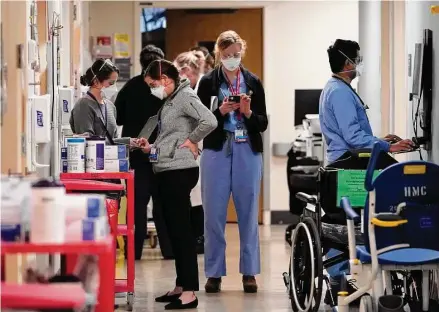  ?? Elaine Thompson/Associated Press ?? Medical workers fill a hallway in the acute-care unit of Harborview Medical Center on Jan. 14 in Seattle, where about half the patients were COVID-19 positive or in quarantine after exposure. The declaratio­n of a COVID-19 public health emergency three years ago changed the lives of millions of Americans by offering increased health care coverage, beefed-up food assistance and universal access to coronaviru­s vaccines and tests. Much of that is now coming to an end, with President Joe Biden’s administra­tion saying it plans to end the emergencie­s declared around the pandemic on May 11.