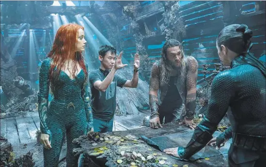  ?? Photograph­s by Jasin Boland DC Comics ?? JAMES WAN sets up a shot with his “Aquaman” cast Amber Heard (warrior princess Mera), titular superhero Jason Momoa and Willem Dafoe, who plays his uncle.