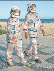  ?? AP ?? A couple dressed in astronaut costumes walk along Ipanema beach in Rio de Janeiro, Brazil.