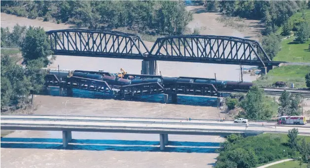  ?? LARRY MACDOUGAL/ THE CANADIAN PRESS ?? Crews work at the scene of a rail bridge collapse and railcars derailment Thursday over the Bow River, southeast of downtown Calgary.