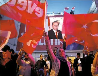  ?? Emrah Gurel/Associated Press ?? Supporters of Justice and Developmen­t party wave Turkish flags Sunday and hold a poster of Turkish President Recep Tayyip Erdogan outside its offices in Istanbul.