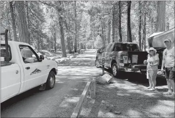  ?? / Union Democrat ?? Shelly Thorene Pinecrest staff stop to remind campers Rina and James Zertuche that they must check out of the campground (above).the campground­s at Pinecrest were mostly empty Tuesday afternoon (left). A sign at Pinecrest (below) states: “Stanislaus National Forest is currently closed until further notice due to extreme fire danger.”