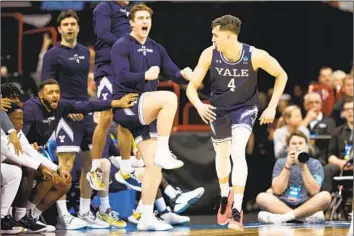  ?? Steph Chambers Getty Images ?? JOHN POULAKIDAS, who scored a game-high 28 points, enjoys the aftermath of one of his three-pointers in the second half with his Yale teammates in a first-round upset of fourth-seeded Auburn at Spokane, Wash.