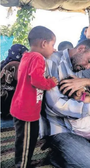  ??  ?? > Haroon Ali (second from right) and Zubair Wani (far right) reviewing a young pyrexial child at a Syrian refugee camp