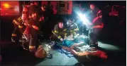  ?? COURTESY OF THE SAN MATEO COUNTY SHERIFF’S OFFICE ?? Medical personnel treat a woman who was pulled from a burning trailer on East Bayshore Road on Feb. 10.