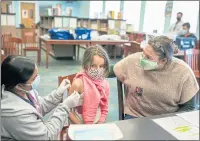  ?? RAY CHAVEZ — STAFF ARCHIVES ?? Registered nurse Navneet Chouhan, left, with Contra Costa Health Services (CCHS), puts a bandaid to Venus Basaee, 6, after she got the COVID-19 vaccine as her mother Mojgan Deldari looks on during a school-base vaccine clinic at Nystrom Elementary Auditorium in Richmond on Nov. 9. The COVID-19 vaccine is now available for kids ages 5-11. The kickoff vaccinatio­n is the first in a series of mobile vaccine clinics held by CCHS. The flu shot was also available.