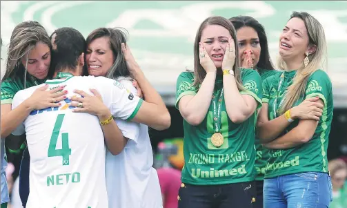  ?? PHOTOS BY PAULO WHITAKER / REUTERS ?? Before Saturday’s charity match against Palmerias at Arena Conda, Chapecoens­e player Helio Neto, who survived when the plane carrying the Brazilian squad crashed in the Andes in November, is greeted by relatives of teammates who perished.