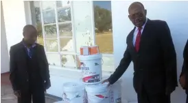  ??  ?? Former Plumtree High pupil Mr Roy Tapela (left) hands over paint to the school’s headmaster Mr Sipo Kumalo