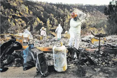  ?? Photos by Gabrielle Lurie / The Chronicle ?? Top: EPA contractor­s cleaning toxic materials carry propane tanks through a property destroyed by the Camp Fire.