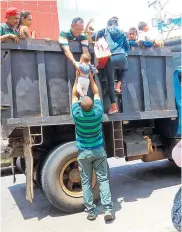  ??  ?? Un hombre ayuda a subir a un menor a una volqueta que pasará por la frontera desde Maicao.