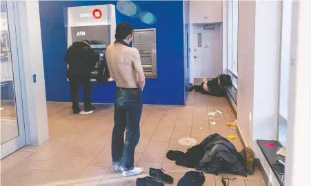  ?? RICHARD LAM ?? A man uses an ATM at the Bank of Montreal, where homeless individual­s have taken refuge in the lobby. The almost daily costs of repairing damage and cleaning up garbage and even feces from building entrances is just part of the escalating crisis gripping the Downtown Eastside.