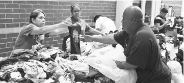  ??  ?? Volunteers sort through donated clothing items at a shelter which will be distibuted to families displaced after their neighborho­ods were inundated with rain water following Hurricane Harvey in Channelvie­w, Texas. — AFP photo