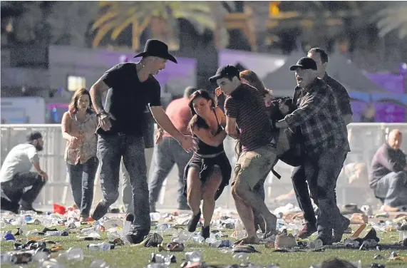  ?? Picture: Getty. ?? People carry an injured fan to safety at the Route 91 Harvest country music festival as a gunman shoots at them in Las Vegas.