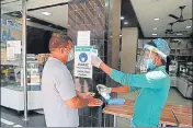  ??  ?? An employee checks temperatur­e of a customer before allowing him to enter the bakery in Srinagar on Thursday. WASEEM ANDRABI/HT