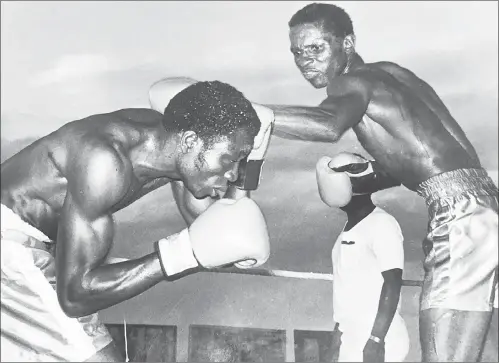  ??  ?? THE GOLDEN BOY . . . Legendary Zimbabwean boxer Langton “Schoolboy” Tinago (right) prepares to fire a big right onto the head of Nigeria’s Safin Oke Badan during their showdown in 1981