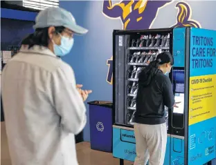  ?? REUTERS ?? People wearing masks queue up at a vending machine, placed by UC San Diego on campus for students and teachers to self-administer COVID-19 tests, in San Diego, Calif., on Tuesday.
