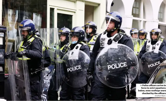  ?? Jonathan Myers ?? > Police officers arrive in force to evict squatters; below, even rooftops were checked by the officers