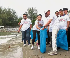  ?? — Bernama ?? Keeping clean: Anwar and other volunteers collecting garbage at the coast of Pantai Cahaya Negeri in Port Dickson.