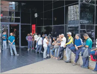 ?? MARCO BELLO /REUTERS ?? Movimiento. La gente hacía cola ayer para retirar efectivo de un cajero del Banco de Venezuela en Caracas.