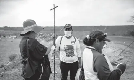  ?? FELIX MARQUEZ/AP 2019 ?? Lidia Lara Tobon, center, whose brother went missing, works with others searching for clandestin­e graves at a municipal dump.