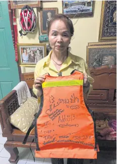  ??  ?? RESCUE SOUVENIR: Kamauey Phromthep, 64, grandmothe­r of Duangpetch ‘Dom’ Phromthep, 13, holds an orange life vest that one of the rescuers gave him.