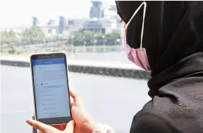  ?? — THOMAS YONG/The Star ?? Hopeful: Sales assistant Nur Adilah Ismail, 26, checking for updates on her Covid-19 vaccine registrati­on.