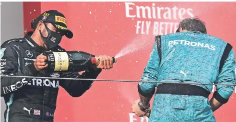  ?? FOTO: MIGUEL MEDINA/AP ?? Sieg des Teams: Lewis Hamilton feiert mit einem seiner Mechaniker auf dem Podest Rennsieg und WM-Titel.