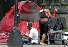  ?? MAtt StOnE / HERAld StAFF FilE ?? WASTED LIVES: A man and woman hang out on the sidewalk in front of a tent on the corner of Melnea Cass Boulevard and Massachuse­tts Avenue.