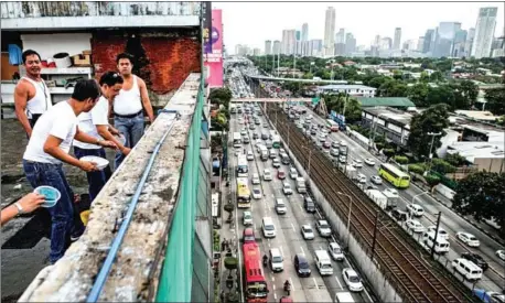  ?? AFP ?? Metro Manila Developmen­t Authority employees wash dishes as traffic is seen past Manila’s financial district. Philippine President Rodrigo Duterte has tapped a China-backed lender to help fund his government’s ‘unpreceden­ted infrastruc­ture buildup’.