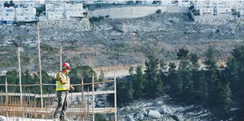  ?? (Ronen Zvulun/Reuters) ?? A LABORER works yesterday at a constructi­on site in Jerusalem’s northweste­rn neighborho­od of Ramot, with the Ramat Shlomo neighborho­od in the background.