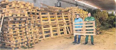  ?? FOTO: TOBIAS SCHUMACHER ?? Dominik Lubrich (l.) und Andreas Angele schichten diese Woche die letzten Paletten auf in einer Halle, in der seit Monaten Brennmater­ial für den ersten Funken der Isnyer Feuerwehr seit einem Jahrzehnt gesammelt wird.