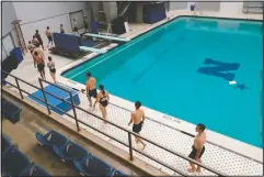  ?? (AP/Julio Cortez) ?? Midshipmen walk in a line as they make their way to the five-meter platform to dive onto a pool at the end of a swim class.