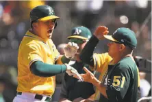  ?? Christian Petersen / Getty Images ?? Ryon Healy high-fives teammates after his solo homer in the seventh, his second of the day. He finished 4-for-4.