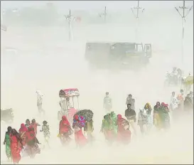  ?? SANJAY KANOJIA / AFP ?? People make their way through the whirling winds of a sandstorm at Sangam, the confluence of three of the holiest rivers in Hindu mythology — the Ganges, Yamuna and Saraswati — on April 23 in Allahabad, eastern Uttar Pradesh, India. Sangam is a famous place of pilgrimage in the South Asian nation.