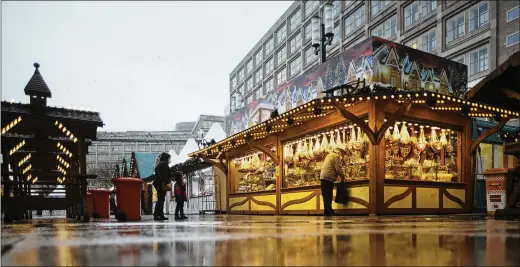  ?? MARKUS SCHREIBER/ASSOCIATED PRESS ?? Customers wait in front of the Christmas Market on a rainy morning in central Berlin, Germany, late last month. Holiday shopping is expected to drop off as nations put in safeguards to protect against the omicron variant of the coronaviru­s.