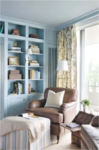  ??  ?? &gt; Above: An ottoman helps turn a comfortabl­e chair into the perfect place for reading in this home library designed by Kelley Proxmire.