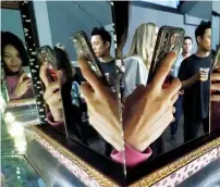  ?? AFP ?? The hand of a visitor taking a photo with a cell phone is reflected in mirrors at the Museum of Selfies in Glendale, California. —