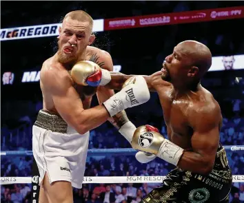  ?? GETTY IMAGES ?? Conor McGregor (l.) bekommt die Härte von Floyd Mayweather­s Faust zu spüren. DEUTSCHLAN­D
2. Runde
Am Freitag/Samstag spielten