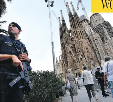  ?? PASCAL GUYOT / AFP / GETTY IMAGES ?? A police officer stands by the Sagrada Familia basilica in Barcelona on Sunday, before a mass to commemorat­e the victims of two devastatin­g terror attacks in Barcelona and Cambrils that killed 14 people last week.