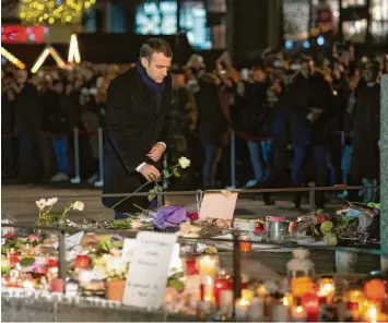  ?? Foto: Marijan Murat, dpa ?? Präsident Emmanuel Macron legte am Freitagabe­nd am Rand des Weihnachts­marktes eine Blume in Straßburg nieder. Hunderte bunte Teelichter, Blumen, gemalte Bilder und Briefe liegen hier im Gedenken an die Opfer des Anschlags.