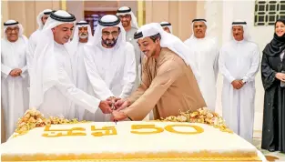  ?? Wam ?? Sheikh Mohammed, flanked by Lt.-General Sheikh Saif bin Zayed Al Nahyan, Deputy Prime Minister and Minister of the Interior; and Sheikh Mansour bin Zayed Al Nahyan, Deputy Prime Minister and Minister of Presidenti­al Affairs; cuts a cake on Tuesday to mark the 50 years of his service to the nation. —